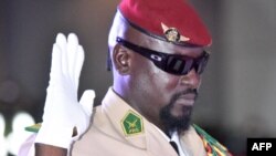 Le chef de la junte guinéenne, le colonel Mamady Doumbouya, lève la main lors de sa prestation de serment en tant que président de la transition du pays, le 1er octobre 2021 à Conakry. (Photo AFP/ Cellou BINANI)