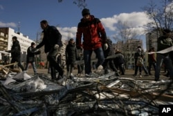17일 우크라이나 수도 크이우(러시아명 키예프) 시민들이 시내 병원 폭격 잔해를 청소하고 있다. 이날 병원과 아파트 등에 미사일 공격이 감행된 가운데, 일부를 요격했다고 우크라이나 당국이 밝혔다,