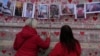FILE: Family members write a message to two sisters who died of COVID on the National Covid Memorial wall in London, March 29, 2022.