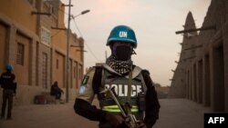 FILE - Policemen of the United Nations Stabilization Mission in Mali (MINUSMA) patrol in front on the Great Mosque in Timbuktu, Mali, Dec. 8, 2021.