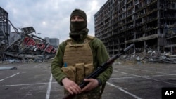 Seorang tentara Ukraina tampak berjaga di lokasi pusat perbelanjaan yang telah hancur akibat serangan Rusia di Kyiv, pada 30 Maret 2022. (Foto: AP/Rodrigo Abd)