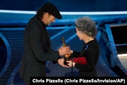Youn Yuh-jung, right, presents Troy Kotsur with the award for best performance by an actor in a supporting role for "CODA" at the Oscars on Sunday, March 27, 2022, at the Dolby Theatre in Los Angeles.