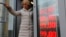 FILE - In this Feb. 24, 2022, photo, a woman leaves an exchange office, where a screen showing the currency exchange rates of the U.S. dollar and euro to Russian rubles is displayed, in Moscow.