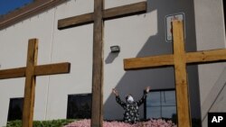 FILE - In this April 12, 2020, photo, a woman in a face mask prays before speaking at an Easter drive-in service in Las Vegas. Calvary Chapel Dayton Valley in rural Nevada fought a 50-person cap on religious gatherings.
