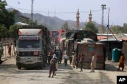 FILE - A Taliban fighter stands guard next to truck waiting to cross at a border crossing point between Pakistan and Afghanistan, in Torkham, in Khyber district, Pakistan, Aug. 21, 2021.