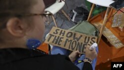 Aktivis perubahan iklim menyiapkan poster bertuliskan "Tunjukkan Pada Kami Mana Uangnya" yang akan digunakan dalam protes dalam konferensi iklim COP27 di Sharm el-Sheikh, Mesir, pada 11 November 2022. (Foto: AFP/Fayez Nureldine)