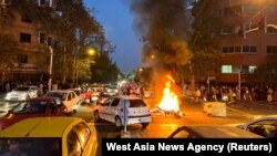 FILE - A police motorcycle burns during a protest over the death of Mahsa Amini, a woman who died after being arrested by the Islamic republic's "morality police", in Tehran, Iran, Sept. 19, 2022. ran's hardline judiciary has indicted 11 people over the k