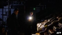 A vendor shows his goods to a customer during a power cut at Bessarabsky market in downtown Kyiv on Nov. 10, 2022.
