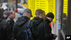 FILE - People stand in line at a currency exchange kiosk in Kyiv, Ukraine.