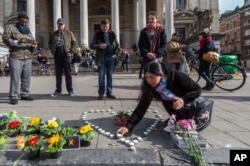 A woman places candles in the shape of a heart outside the stock exchange in Brussels, March 22, 2016.