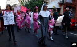A young woman dressed as a nun leads a group of women depicting pregnant schoolgirls in a march marking the International Day for the Elimination of Violence Against Women, in Asuncion, Paraguay, Nov. 25, 2017. According to officials there is at least one femicide reported per week in Paraguay.