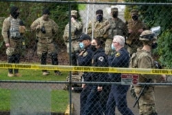 Pasukan Patroli Negara Bagian Washington berjalan di dekat anggota Garda Nasional yang berdiri berjaga-jaga di sepanjang pagar perimeter di Gedung Capitol negara bagian Washington di Olympia, Minggu, 17 Januari 2021.