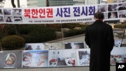 FILE - A man watches photos showing North Korean children suffering from famine at a photo exhibition in Seoul, South Korea, Feb. 27, 2014.