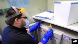 A pharmacy technician from Croydon Health Services prepares to store the first delivery of COVID-19 vaccine, at Croydon University Hospital in Croydon, England, Dec. 5, 2020. 