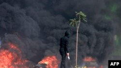 A Palestinian looks at dense black smoke during clashes with Israeli soldiers at the north entrance of the Palestinian city of Ramallah, near Beit El Jewish settlement, in the occupied West Bank on Oct. 13, 2023.