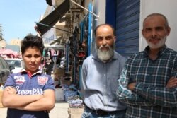 Abdullah, center, and his cousin Mohammed, right, run a shoe store in a Tripoli market, May 2, 2019. They say that since the war began in early April, Tripoli has become poorer, more crowded and scared. (H.Murdock/VOA)