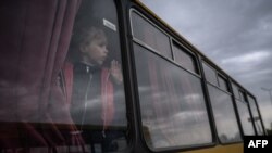 FILE - A girl looks out from a bus as families from Russian occupied territories in Ukraine's Zaporizhzhia region arrive in a humanitarian convoy at a registration and processing center for internally displaced people.
