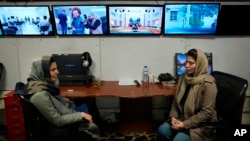 FILE - Afghan journalists Banafsha Binesh, right, speaks with her colleague Wheeda Hassan, at TOLO TV's newsroom in Kabul, Feb. 8, 2022.