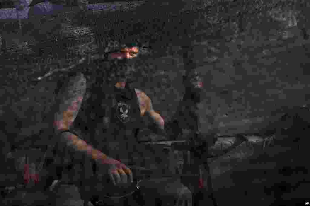 A pro-Russian armed militant sits behind a camouflage net at a checkpoint blocking the major highway which links the Russian city of Rostov-on-Don, and Kharkiv, outside Slovyansk, May 26, 2014.