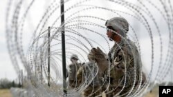 FILE - Members of a U.S Army engineering brigade place concertina wire around an encampment for troops, Department of Defense and U.S. Customs and Border Protection near the U.S.-Mexico international bridge, Nov. 4, 2018, in Donna, Texas.