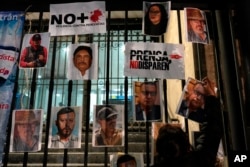 FILLE - A woman posts photos of murdered journalists during a national protest against the murder of journalists Lourdes Maldonado and freelance photojournalist Margarito Martínez in Mexico City, Jan. 25, 2022