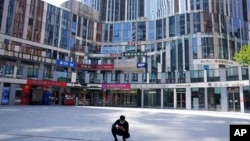 一名男子蹲在北京一处被关闭了的商场前。（ 2022年5月2日