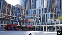 A man wearing a mask squats in front of an empty mall area in Beijing, May 2, 2022.