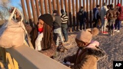 FILE - A Cuban woman and her daughter wait in line to be escorted to a Border Patrol van for processing in Yuma, Ariz., on February 6, 2022, hoping to remain in the United States to seek asylum.