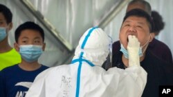 A worker swabs a man for a COVID-19 test during the second consecutive day of mass testing in Beijing, May 4, 2022. To help slow the spread of COVID-19, Beijing closed around 10% of its subway stations and hundreds of bus routes on Wednesday.