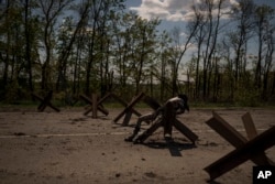 FILE - The body of an unidentified man lies on a road barrier near a village on the outskirts of Kharkiv, Ukraine, April 30, 2022.