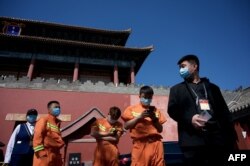 人们在北京紫禁城旁的一个新冠病毒核酸检测点旁排队等候进行检测。（2022年5月1日）