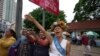 Cambodian-American lawyer Theary Seng, dressed in a pageant costume that reads "Lady Justice", shouts slogans outside Phnom Penh Municipal Court in Phnom Penh, Cambodia, Tuesday, May 3, 2022. 
