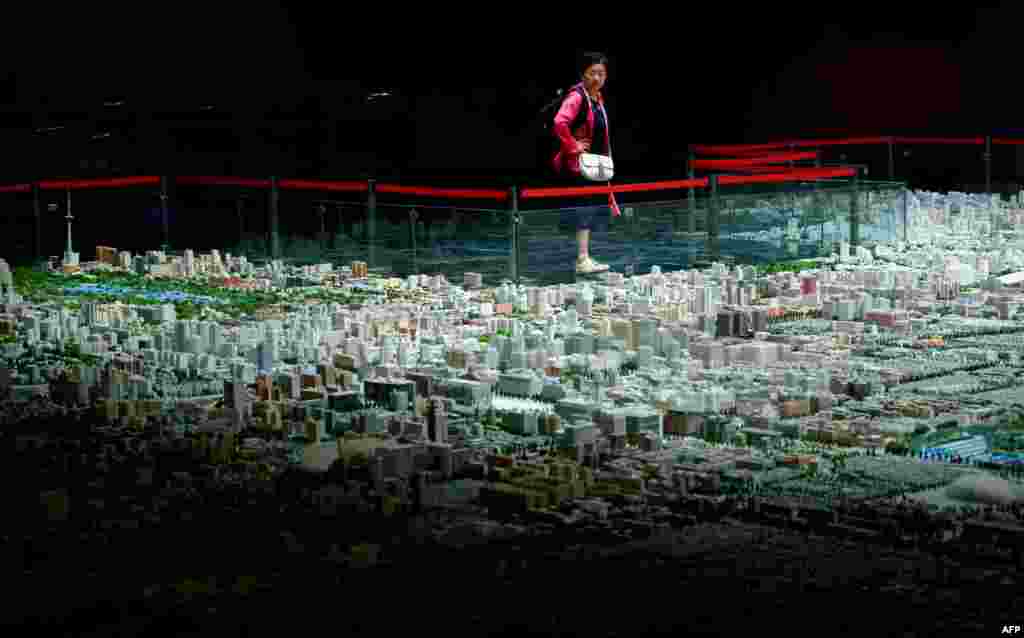 Seorang perempuan mengamati model kota Beijing pada sebuah pameran di Beijing, China.