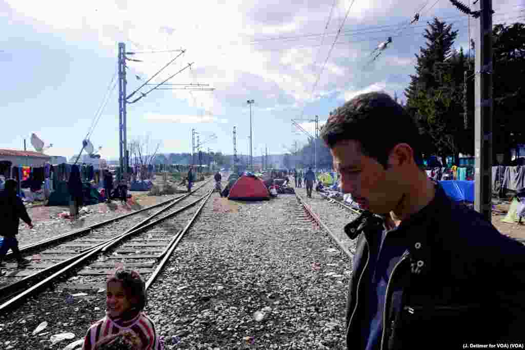 A man walks amid a makeshift encampment, with tents set up between train tracks in the northern Greek border town of Idomeni, March 4, 2016.