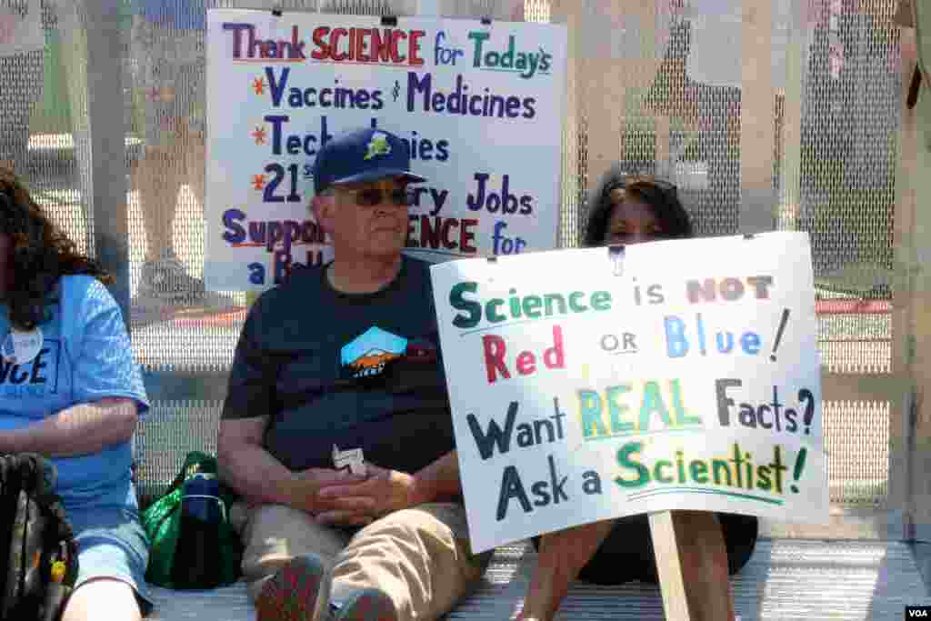 ក្រុម​អ្នក​តវ៉ា​សម្រាក​នៅ​ជិត​ឆាក​នៃ​ចលនា​ដើរ​ជា​ក្បួន​ដើម្បី​លើក​កម្ពស់​វិទ្យាសាស្ត្រ។ (ចាប ចិត្រា/VOA)