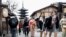 Turis berjalan di jalanan dekat Pagoda Yasaka (belakang) saat berkunjung ke kota Kyoto, 13 Januari 2025. (PAUL MILLER / AFP)