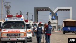 Waandishi wa habari wakichukua picha za video wakati magari ya wagonjwa ya wizara ya afya ya Palestina yakivuka lango kuingia katika kivuko cha Rafah upande wa kusini mwa Ukanda wa Gaza kabla ya kuingia Misri Novemba 1, 2023.