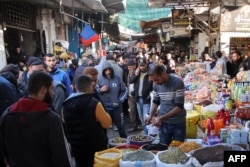 A pickle vendor serves a customer from his stall at the old Zawiya market of Gaza City on the first day of the holy fasting month of Ramadan on March 1, 2025, amid the ongoing truce in the war between Israel and Hamas.