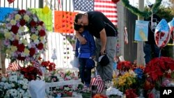 លោក Gary Mendoza និង​កូន​ប្រុស​ឈ្មោះ Michael កាល​ពី​ថ្ងៃ​ច័ន្ទ ទី​៧ ខែ​ធ្នូ ឆ្នាំ​២០១៥ សម្តែង​​គារវកិច្ច​នៅ​បូជនីយដ្ឋាន​បណ្តោះ​អាសន្ន​​មួយ​កន្លែង​​​សម្រាប់​អ្នក​រង​ការ​បាញ់​ប្រហារ​​នៅ​ក្រុង San Bernardino រដ្ឋ California។