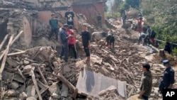 Nepalese villagers stand amidst the debris of their mudhouses after an earthquake in Doti district, Nepal, Wednesday, Nov.9, 2022.
