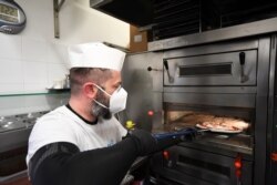 A man bakes a pizza at a restaurant, as Tuscany is the first Italian region to allow restaurants to open only for takeout in Castiglione della Pescaia, April 27, 2020.