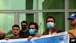 In this Friday, April 30, 2021, photo former Afghan interpreters hold banner during a protest against the U.S. government and NATO in Kabul, Afghanistan. 
