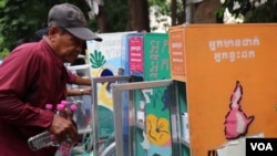 អ្នកធាក់ស៊ីក្លូ​កំពុងរៀបចំគ្រឿងបរិភោគដាក់ចូលធុង «អ្នកមានដាក់ អ្នកខ្វះដក» យកទៅចែកអ្នកក្រខ្សត់នៅ ក្នុងរាជធានីភ្នំពេញ កាលពីថ្ងៃទី២៩ ខែឧសភា ឆ្នាំ២០២២។ (លាស់ លីបលីប/វីអូអេ)