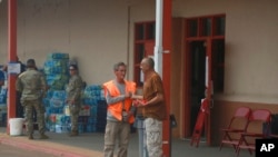Wildfire evacuees Paul T. Vigil, center left, and Domingo Martinez, both of Manuelitas, NM, greet each other at a shelter and supply depot at a middle school in Las Vegas, NM, on May 7, 2022.
