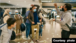 US dollar bills shower Afghan refugee Najeebullah and his family as they arrive at the Seattle International Airport. (Photo by Joshua Trujillo)
