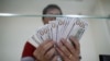 FILE: Bank staff shows U.S. hundred dollars bills at AYA Bank's money changer in Yangon July 17, 2015. REUTERS/Soe Zeya Tun