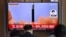 People watch a television screen showing a news broadcast with file footage of a North Korean missile test, at a railway station in Seoul on May 25, 2022.