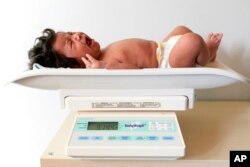 One-month-old baby Charlotte is weighed before attempting to breastfeed, during a lactation consultation in Columbia, Md., May 23, 2022.