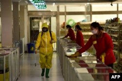 Karyawan menyemprotkan disinfektan di Pyongyang. (Foto: AFP)