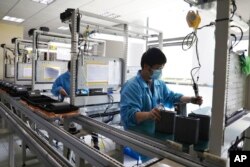 In this photo released by Xinhua News Agency, staff members wearing masks work in an industry park in Qingpu District of Shanghai, east China, May 17, 2022.